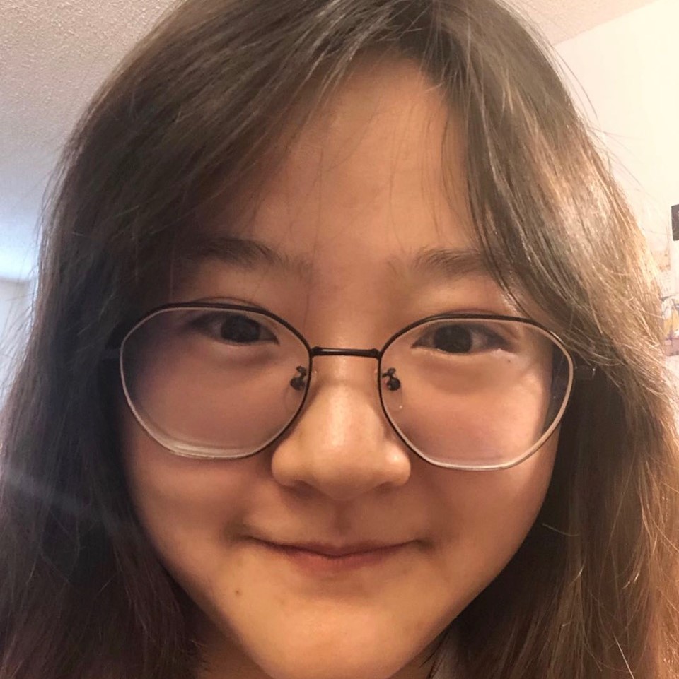 A headshot of a woman with long straight hair and glasses